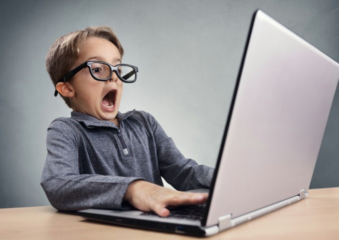 Shocked and surprised boy on the internet with laptop computer concept for amazement, astonishment, making a mistake, stunned and speechless or seeing something he shouldn't see